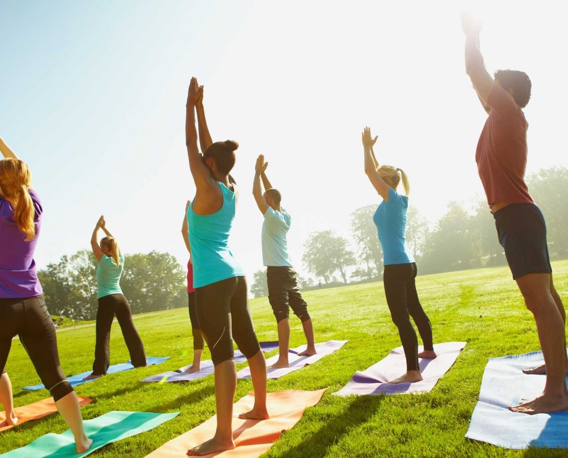 Group on men and women enjoying a yoga class on a golf course