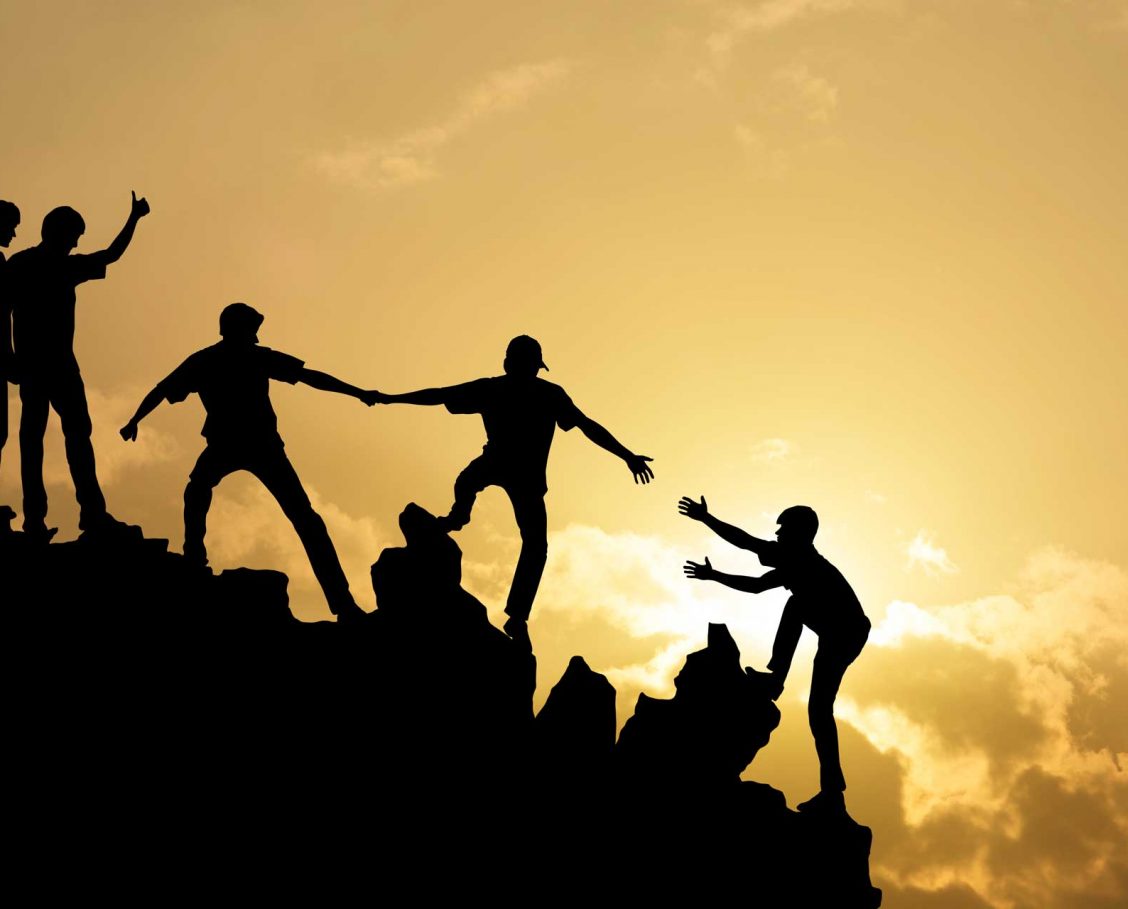 Friends mountain climbing and helping each other up
